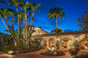Beautiful hacienda style home with palm trees and water fountain in front